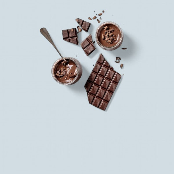 Deux pots de mousse au chocolat garnis d’éclats de chocolat, accompagnés de morceaux de tablette de chocolat noir sur fond gris clair.