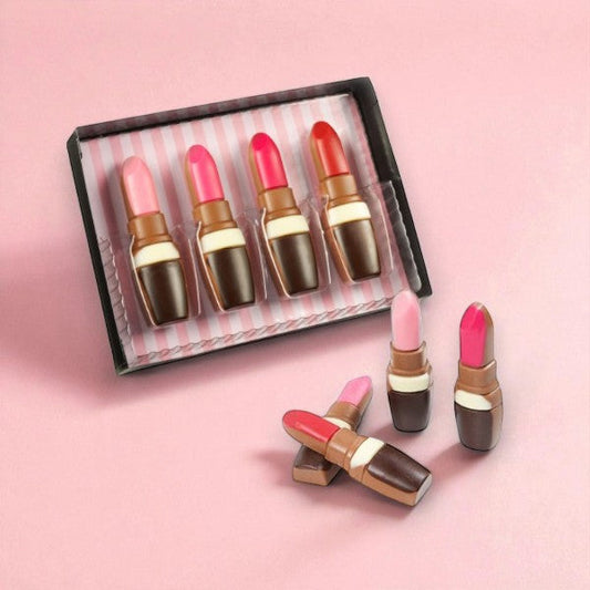 Coffret de rouges à lèvres en chocolat au lait présenté sur fond rose, création insolite et girly pour amateurs de chocolat.