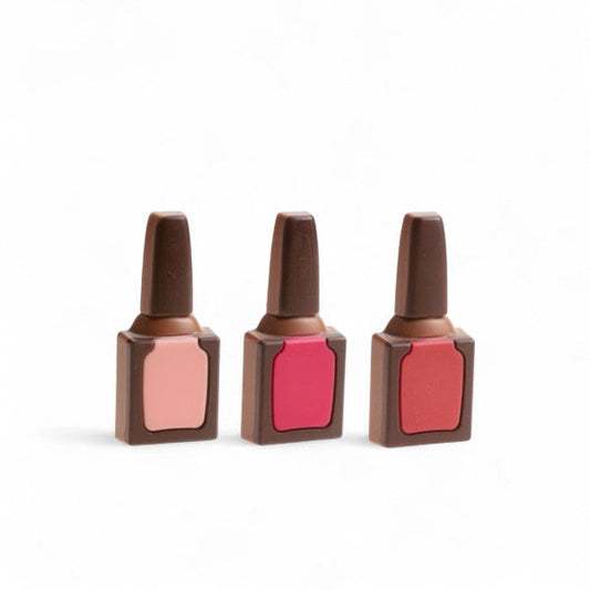 Trois vernis à ongles en chocolat au lait finement moulés et décorés, gourmandise insolite et raffinée.