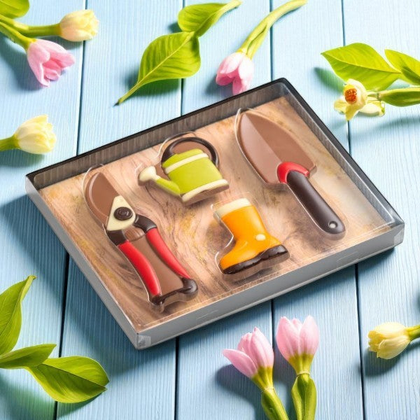 Coffret jardinier en chocolat au lait entouré de fleurs, gourmandise printanière et cadeau original pour passionnés de chocolat et de nature.