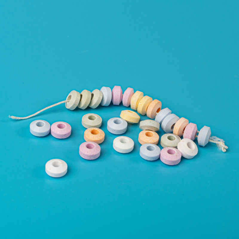 Collier de bonbons en dextrose cassé sur fond bleu, anneaux pastel sucrés au goût acidulé.