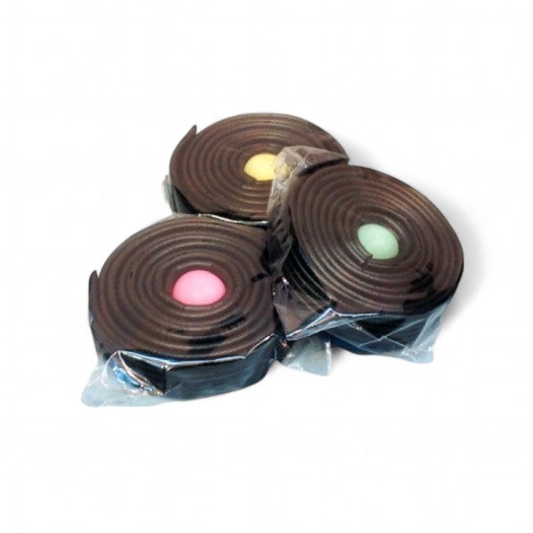 Trois rouleaux de réglisse emballés sur fond blanc, confiseries traditionnelles à la réglisse.