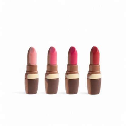 Quatre rouges à lèvres en chocolat au lait décoré, moulage gourmand et original alliant élégance et plaisir sucré.
