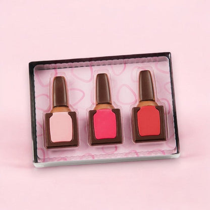 Coffret vernis à ongles en chocolat au lait présenté sur fond rose, cadeau girly et gourmand plein d’élégance et d’originalité.