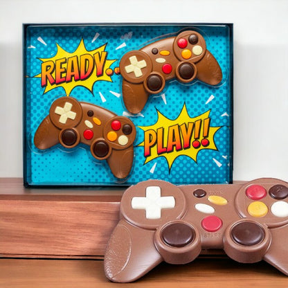 Coffret de manettes de jeux vidéo en chocolat au lait posé sur une table, création ludique et fondante pour gamers gourmands.