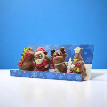Coffret de moulages en chocolat Figurines de Noël 120g sur fond bleu, chocolats au lait et blanc festifs et gourmands.