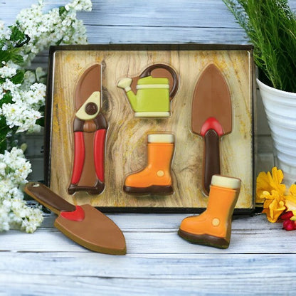 Coffret jardinier en chocolat au lait présenté sur un fond en bois, création chocolatée originale pour amateurs de jardinage et de douceurs.