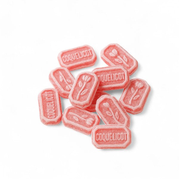 Bonbons Coquelicot en vrac sur fond blanc, confiseries rouges dures à l’arôme naturel de fleur de coquelicot.