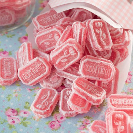 Bonbons Coquelicot en vrac disposés sur une nappe bleue dans un décor authentique, confiseries rouges brillantes au parfum floral.