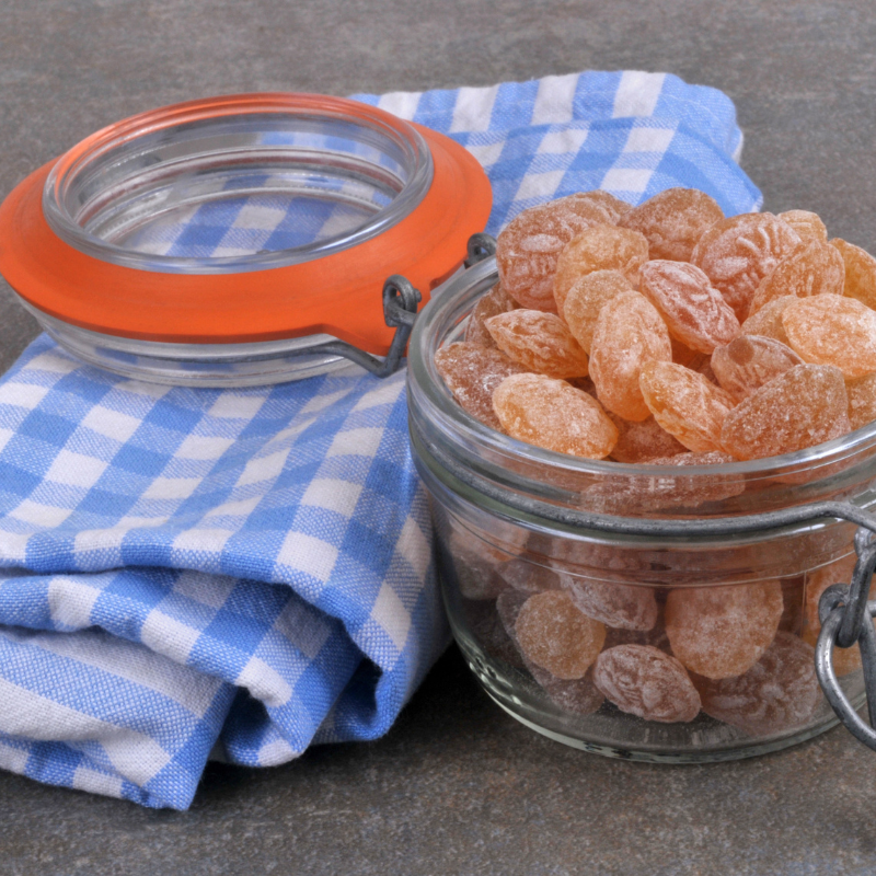 Bonbons Pastilles Miel présentés dans un pot en verre traditionnel avec décor authentique, confiseries dorées au miel naturel.
