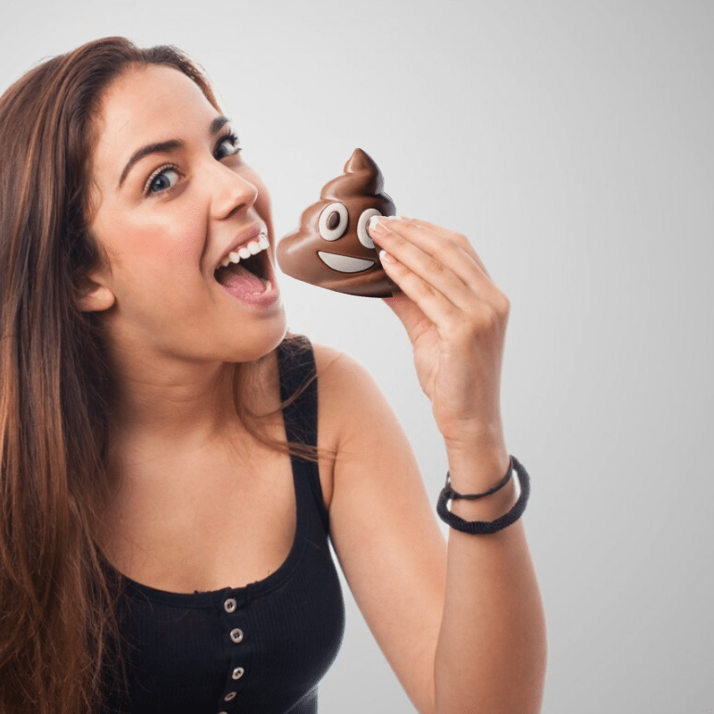 Femme dégustant un emoji « Crotte » en chocolat au lait, moment gourmand et ludique plein d’humour.