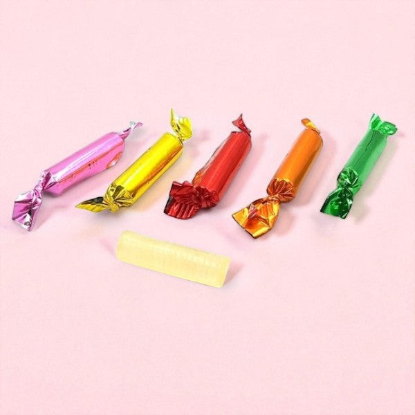 Mini sucres d’orge sur fond rose, confiseries colorées en sucre cuit aux arômes de fruits variés.