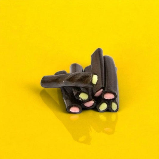 Bonbons Cocobat disposés sur fond jaune, confiseries à la réglisse au goût sucré et texture tendre.