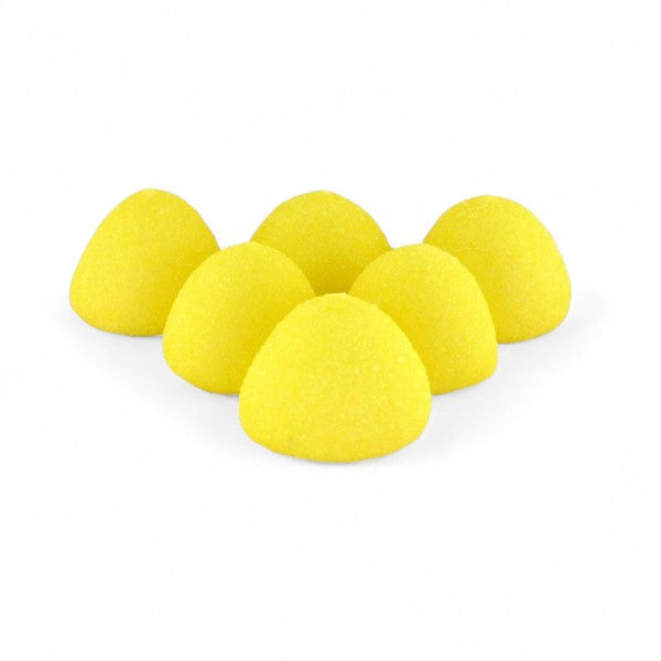 Six guimauves balle de golf goût banane disposées sur une surface blanche, confiseries jaunes moelleuses.