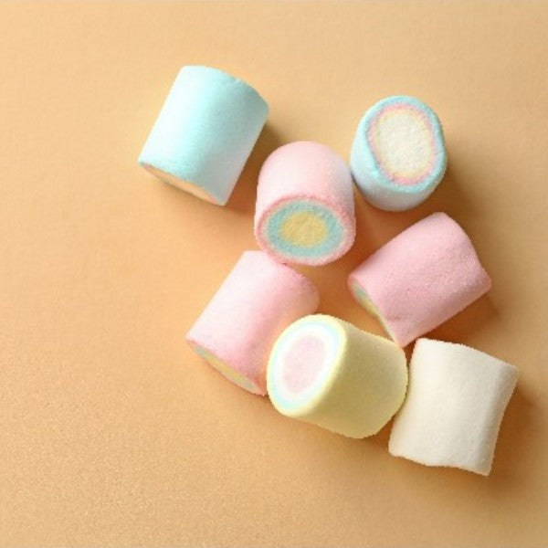 Sept guimauves roulées multicolores goût vanille disposées sur un fond marron, confiseries moelleuses aux couleurs pastel.