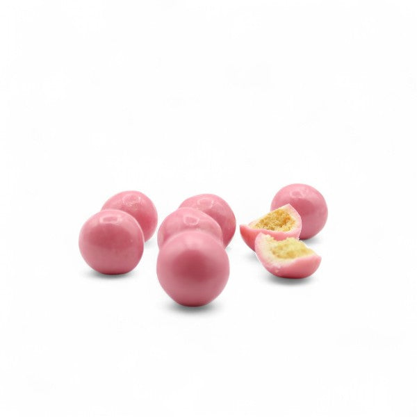 Billes de céréales soufflées enrobées de chocolat blanc et poudre de biscuit rose de Reims présentées en vrac, gourmandises croquantes et élégantes.