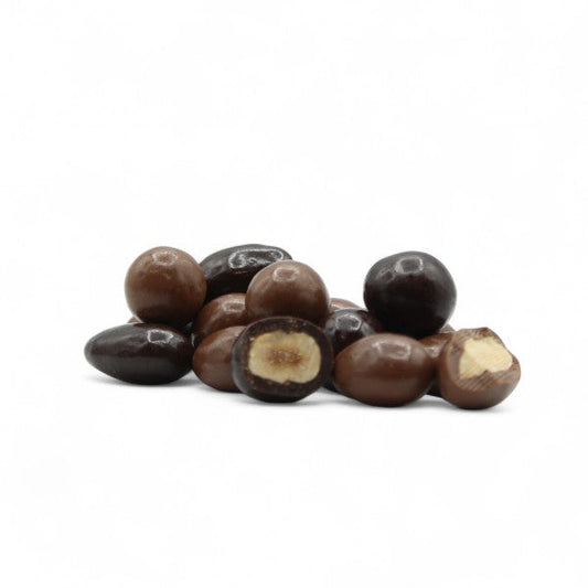 Gros plan d’un mélange gourmand de noisettes et d’amandes enrobées de chocolat au lait et noir, mettant en valeur la texture croquante et le contraste des chocolats.