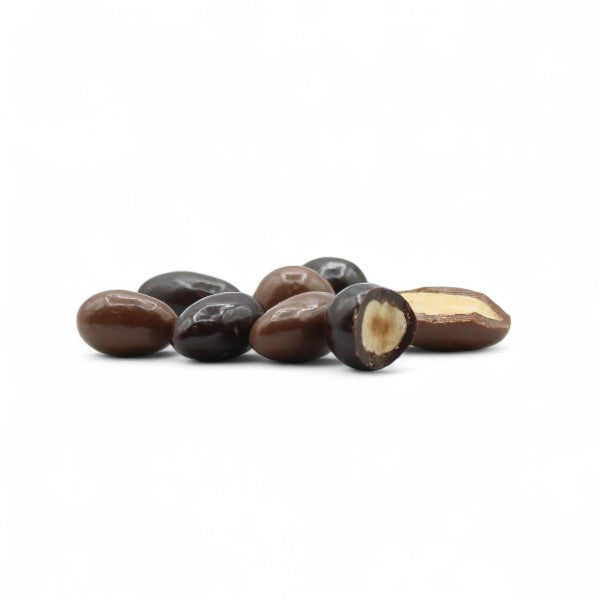 Assortiment de noisettes et d’amandes enrobées de chocolat au lait et noir présenté en vrac, image appétissante d’un mélange croquant et fondant à la fois.