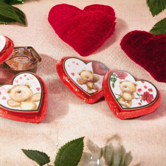 Quatre Cœurs Ourson en chocolat au lait disposés sur une nappe en décoration, gourmandises pralinées aux motifs colorés et joyeux.