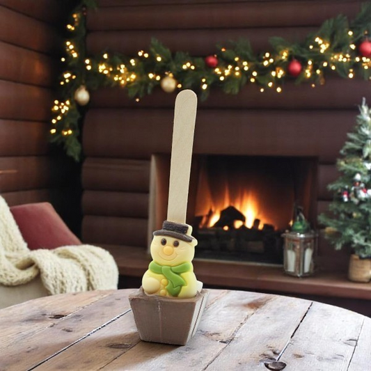 Cuillère à chocolat chaud Noël Bonhomme de neige 55g présentée dans un décor de chalet, gourmandise chocolatée et festive.