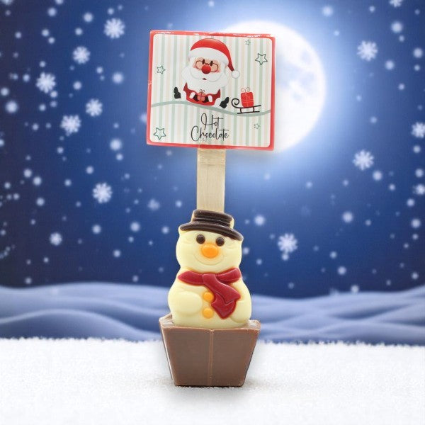 Cuillère à chocolat chaud Noël Bonhomme de neige 55g mise en scène dans un décor de neige et de lune, boisson chocolatée réconfortante.