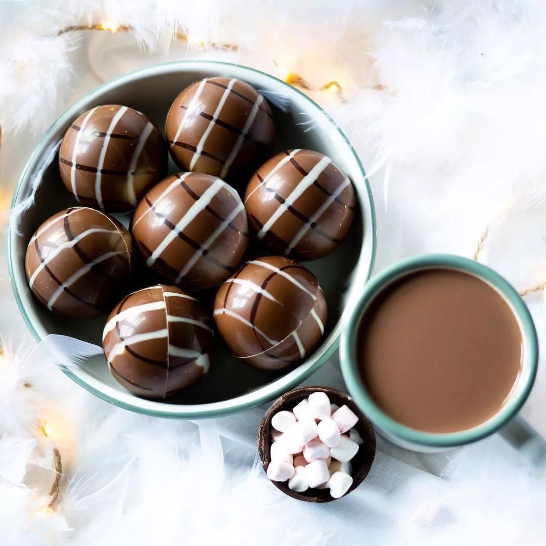 Boules magiques à chocolat chaud 45g présentées dans un bol décoré, chocolat fondant au cœur de mini guimauves pour boisson chaude.