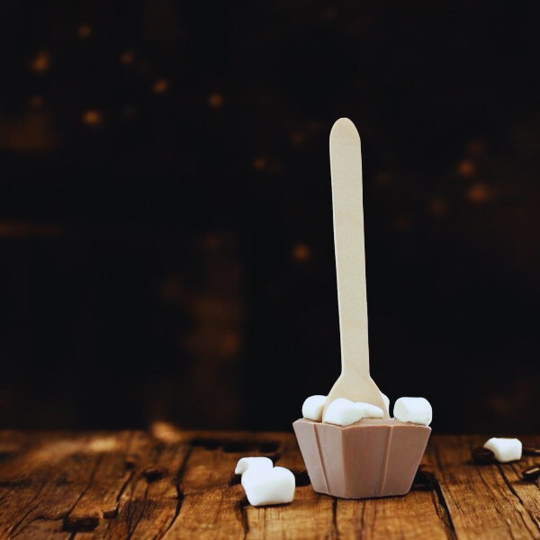Cuillère à chocolat chaud au lait et mini guimauves sur fond bois – douceur fondante et réconfortante.