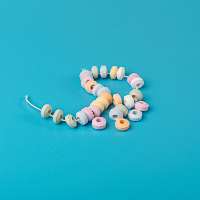 Collier de bonbons en dextrose sur fond bleu, friandises colorées aux teintes pastel au goût sucré et acidulé.