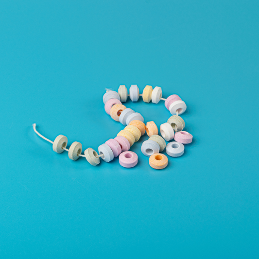 Collier de bonbons en dextrose sur fond bleu, friandises colorées aux teintes pastel au goût sucré et acidulé.