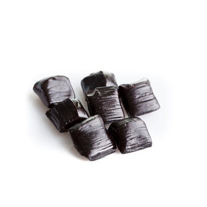 Gros plan sur les réglisses dures italiennes “Spezzata”, gros morceaux irréguliers de réglisse pure à la saveur intense et naturelle.