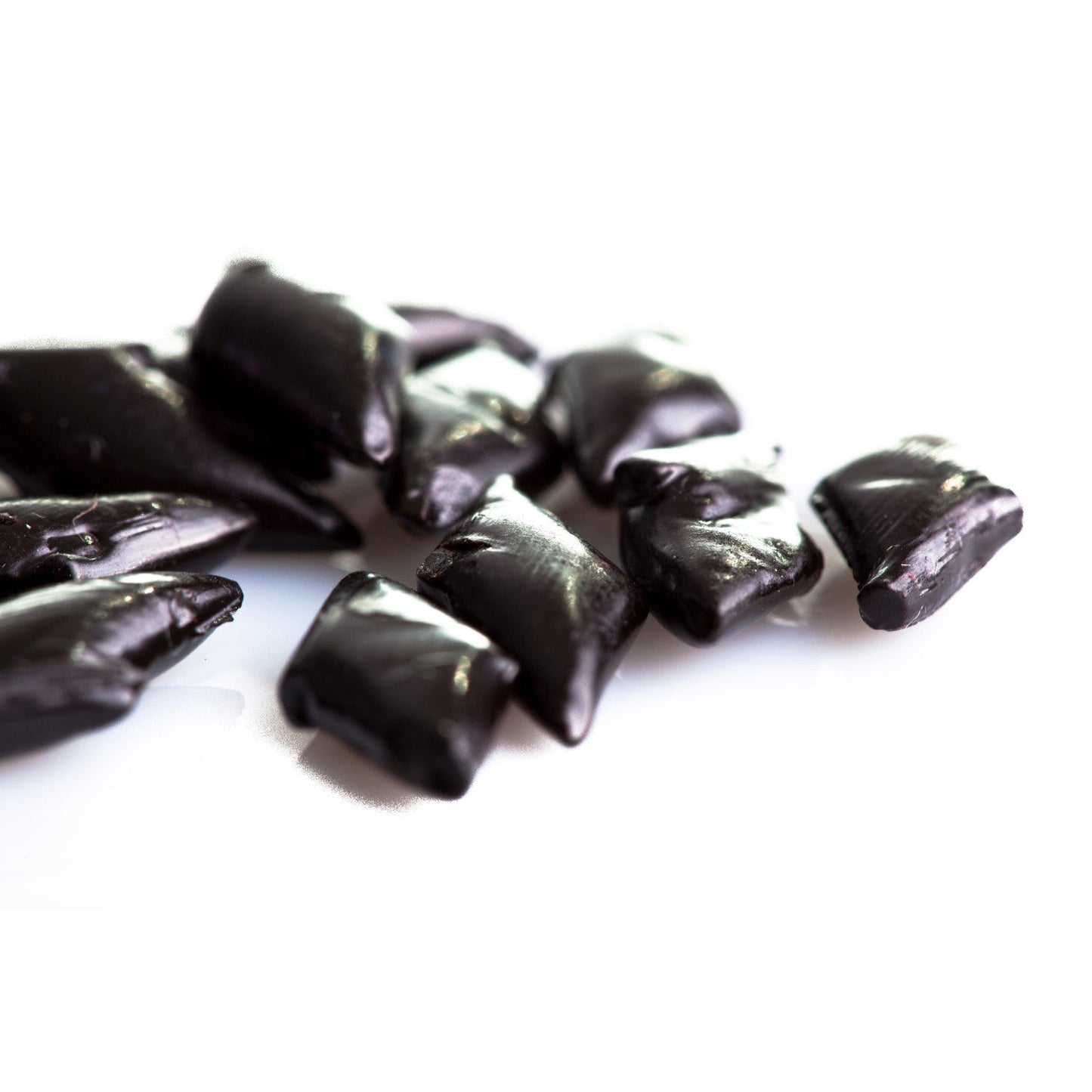 Gros plan sur les réglisses dures italiennes “Rombetti”, petits losanges noirs à l’arôme naturel et délicat d’anis.