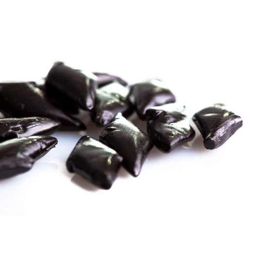 Gros plan sur les réglisses dures italiennes “Rombetti”, petits losanges noirs à l’arôme naturel et délicat d’anis.