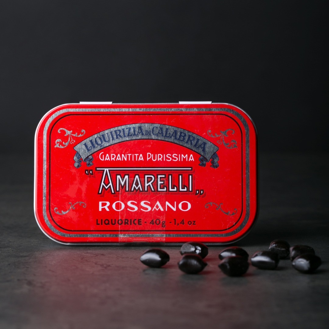 Boîte métallique de réglisses italiennes Spezzatina sur fond sombre, confiserie raffinée à la réglisse au goût authentique.