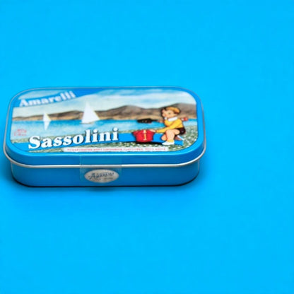 Boîte métallique de réglisses Sassolini sur fond bleu, confiserie italienne à la réglisse et à l’anis, au design élégant.