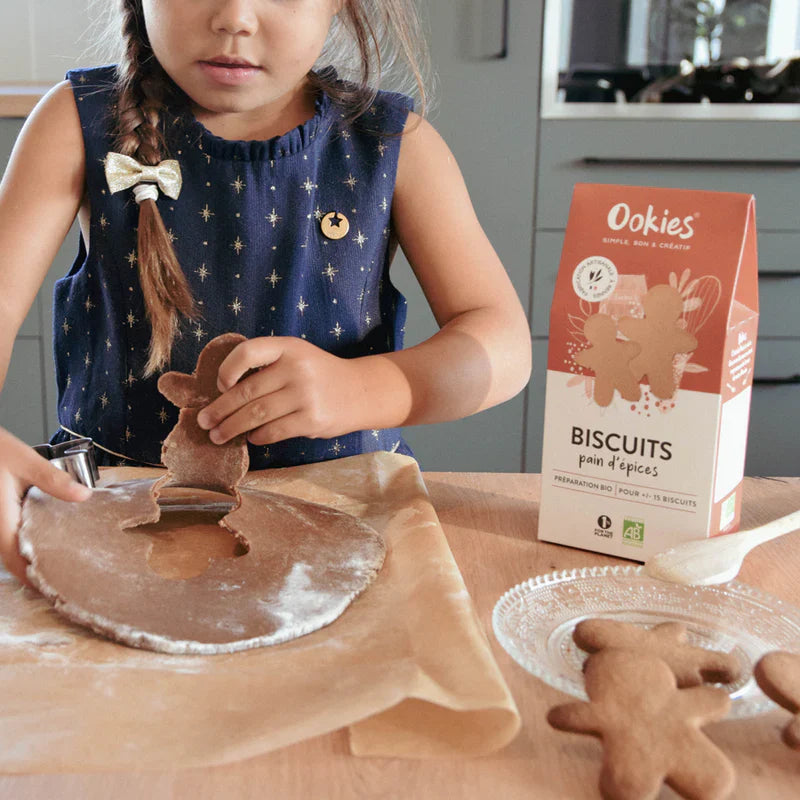 Fillette préparant des biscuits pain d’épices avec la préparation bio, moment ludique et gourmand en cuisine.