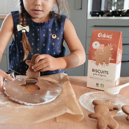 Fillette préparant des biscuits pain d’épices avec la préparation bio, moment ludique et gourmand en cuisine.