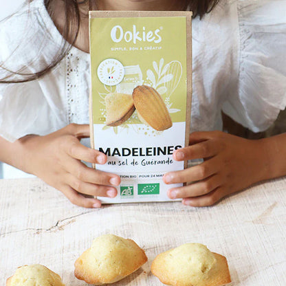 Main d’enfant tenant le sachet de préparation pour madeleines au sel de Guérande 100% bio, plaisir authentique et familial.