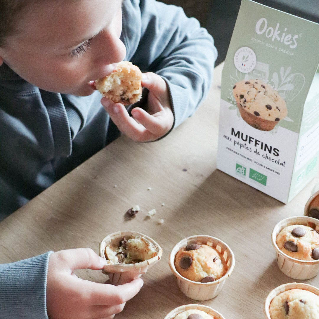 Enfant dégustant un muffin aux pépites de chocolat, moment gourmand et réconfortant autour de muffins faits maison bio.