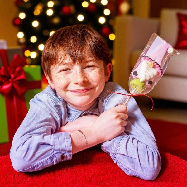 Garçon tenant une brochette guimauve “Gnome” 55g, confiserie de Noël moelleuse et colorée décorée à la main.