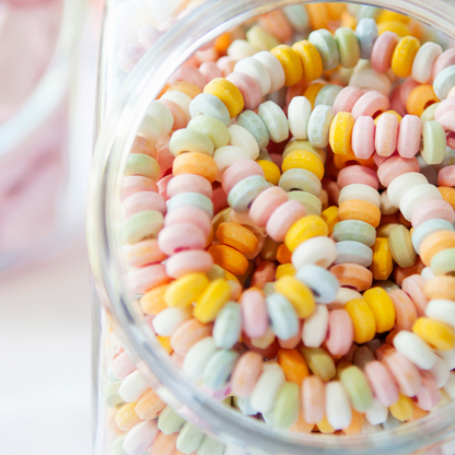 Boîte de 100 colliers de bonbons en dextrose, anneaux colorés pastel enfilés sur un fil élastique.