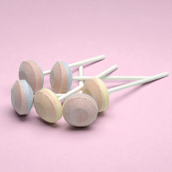 Sucettes lollie dextrose en vrac sur fond rose, sucettes bicolores fruitées en sucre dextrose fondant.