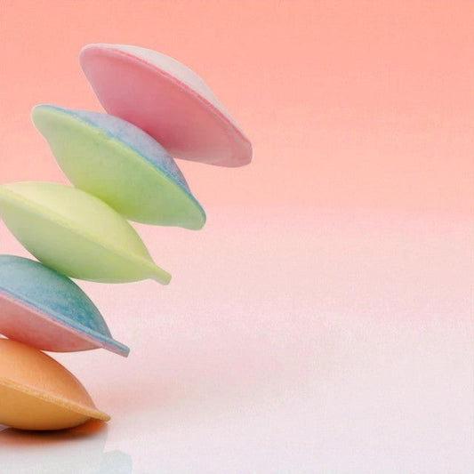 Soucoupes colorées empilées sur fond orangé, bonbons rétro fourrés à la poudre acidulée fruitée.